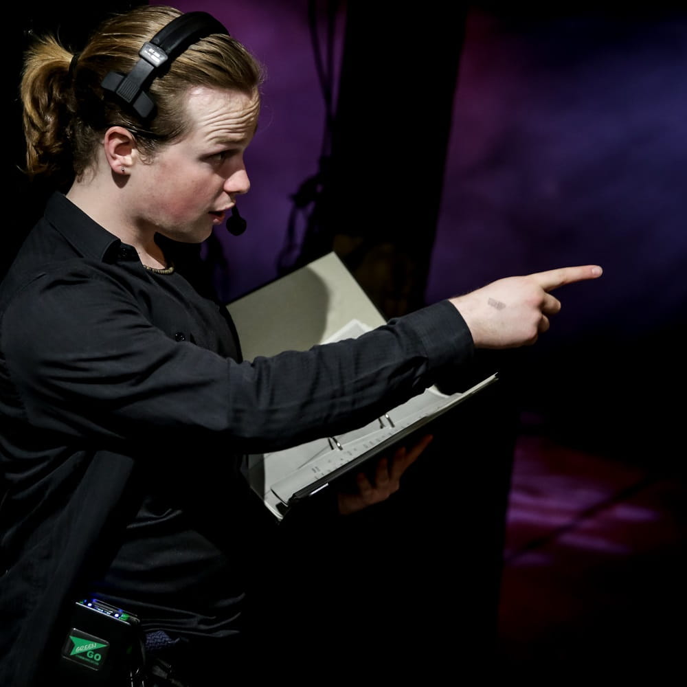 Stage management student giving instructions backstage of an East 15 production