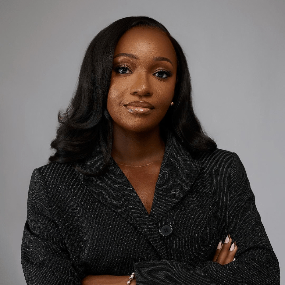 Headshot of Isimeme Ughele, she is wearing a black blazer and her arms are folded.