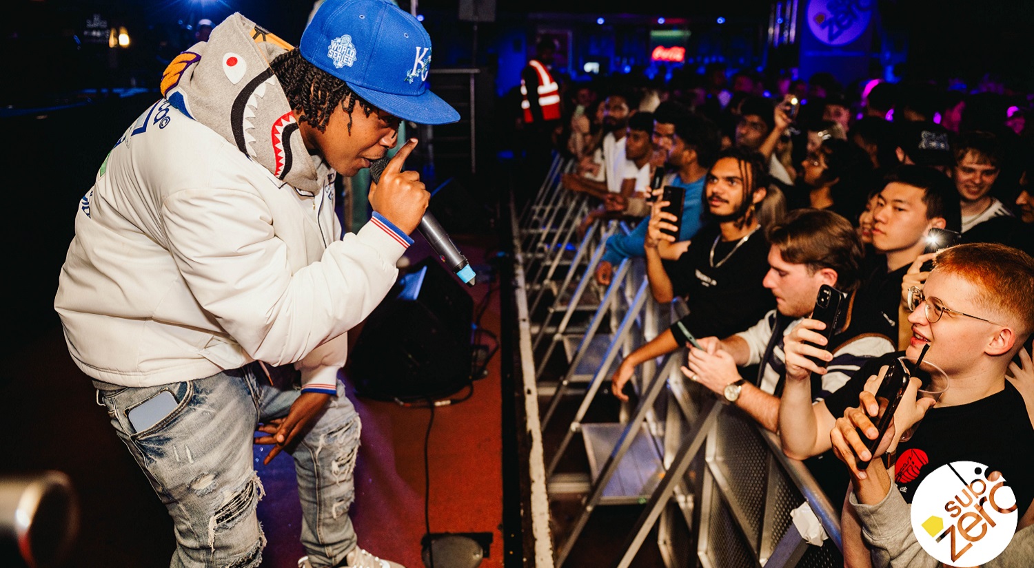 A rap artist on stage to a large crowd at Sub Zero