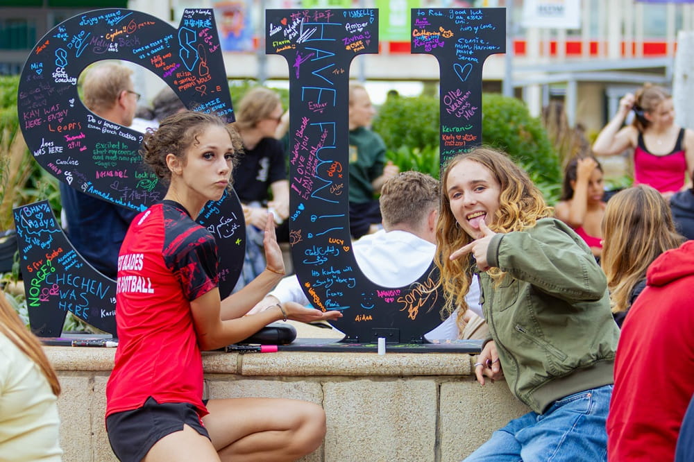 University of Essex football scholar in front of SU sign during Welcome Week