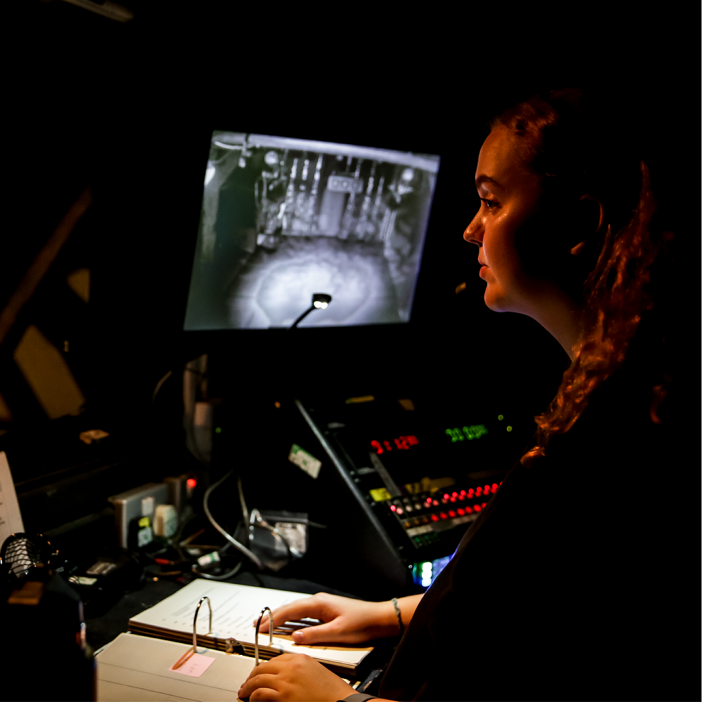 student at a computer desk in a dark room